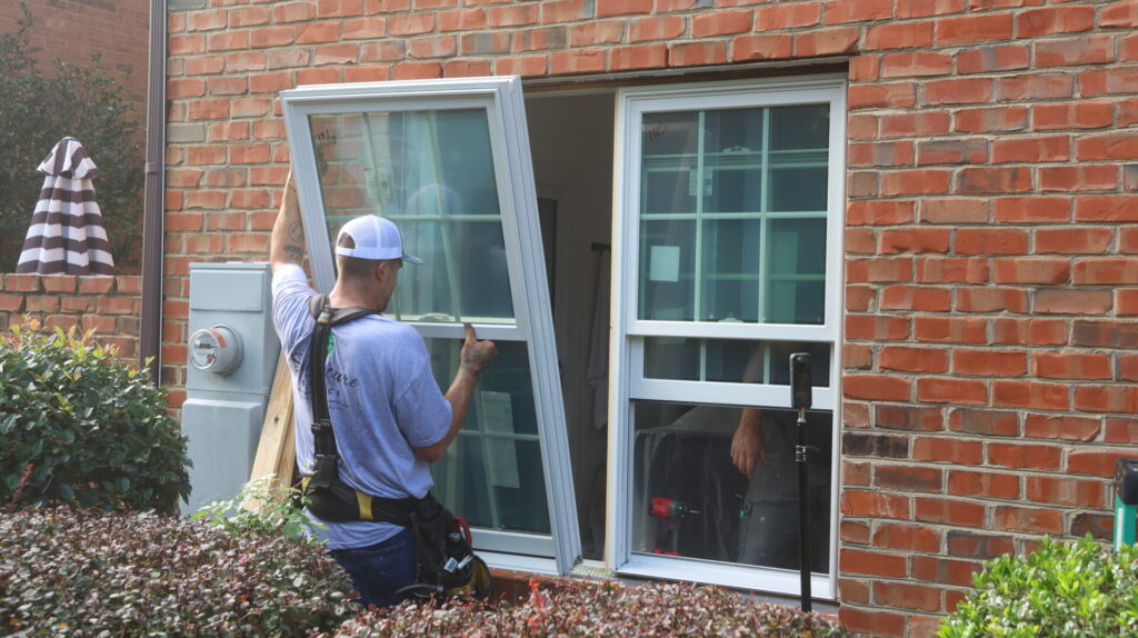 Window installer placing a new window onto a brick home.