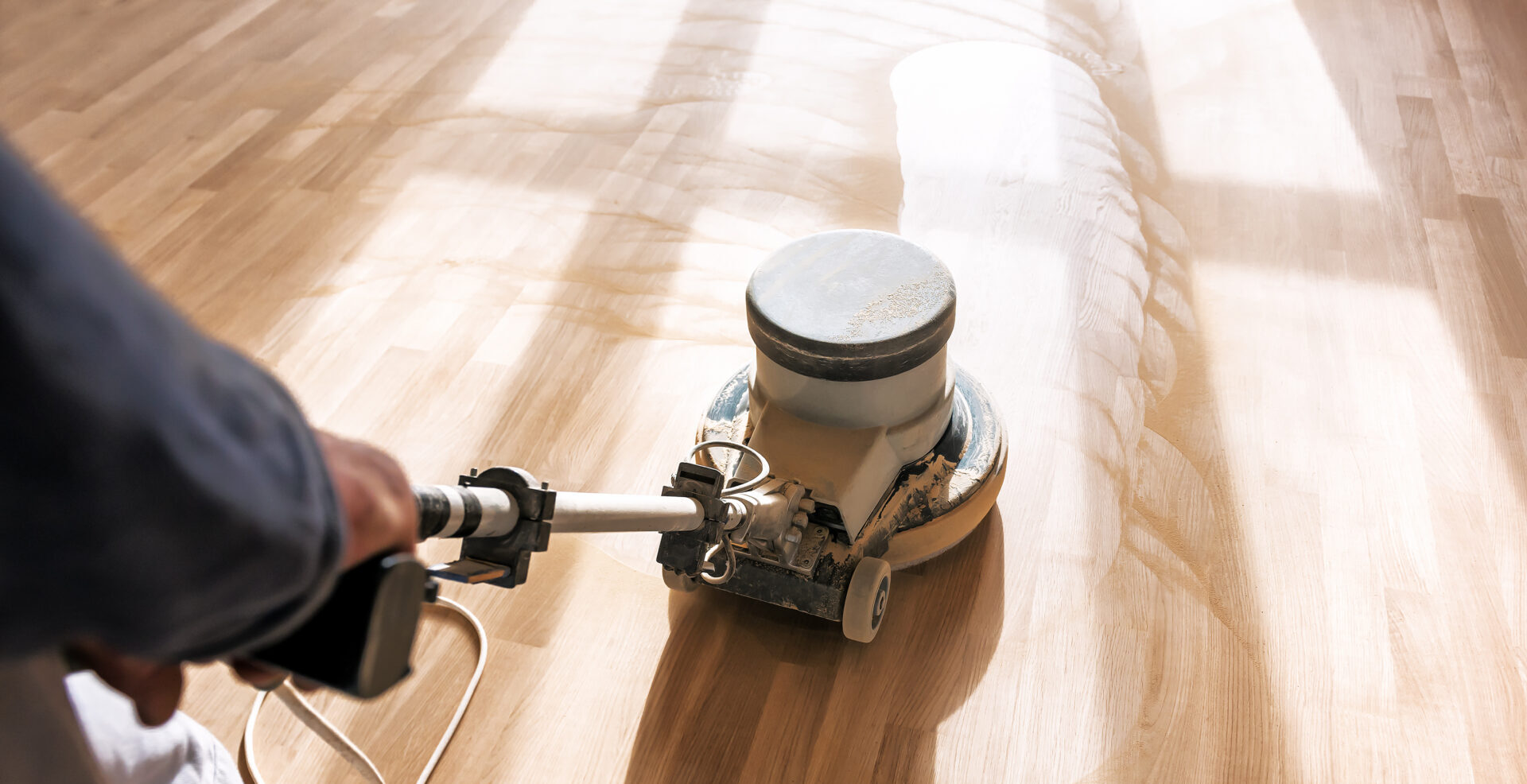 A professional floorer using a floor polishing machine on hardwood floors