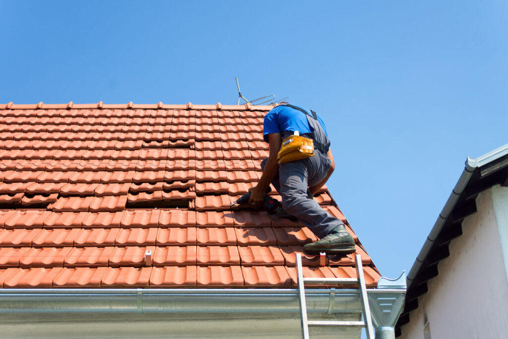 Roofing contractor repairing a tile roof