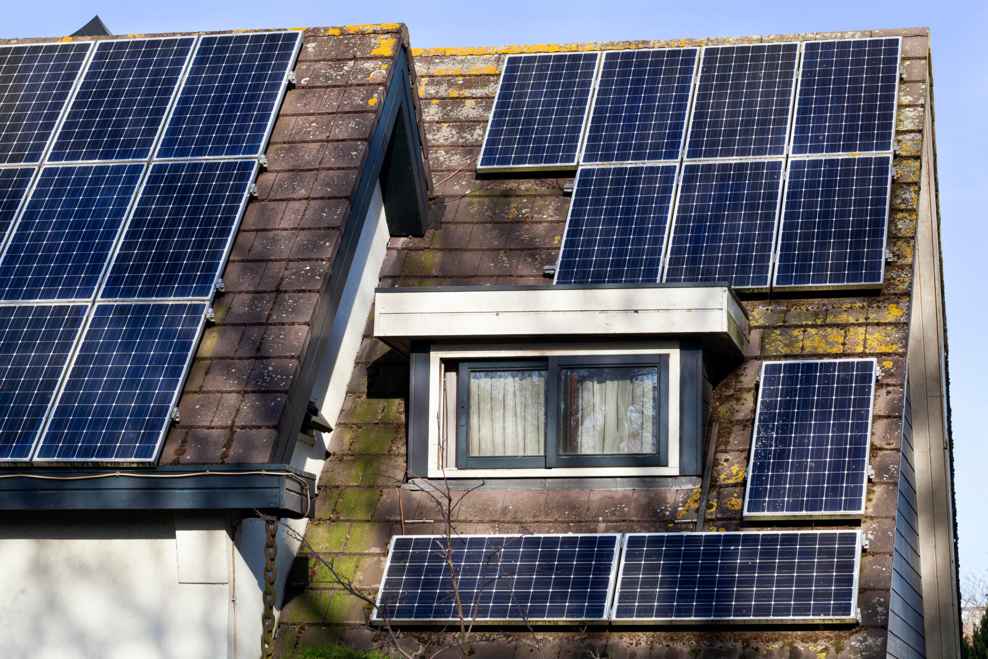 house roof covered with solar panels under a tree's shadow
