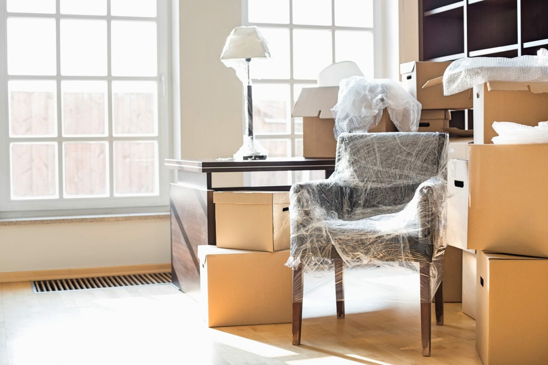 Moving boxes and furniture wrapped up in the office of a home.