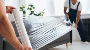 two movers with a moving company in south carolina wrapping a couch in plastic