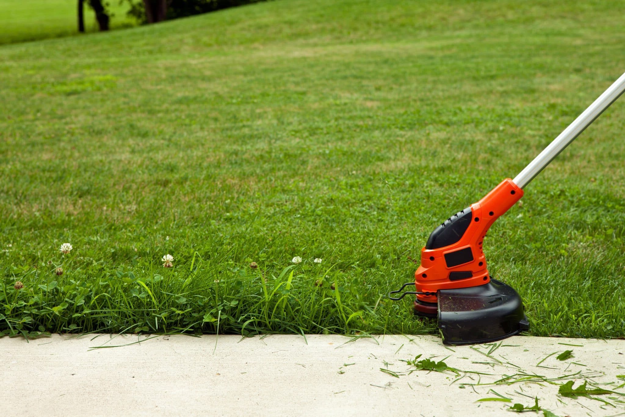 lawn edger trimming along a sidewalk