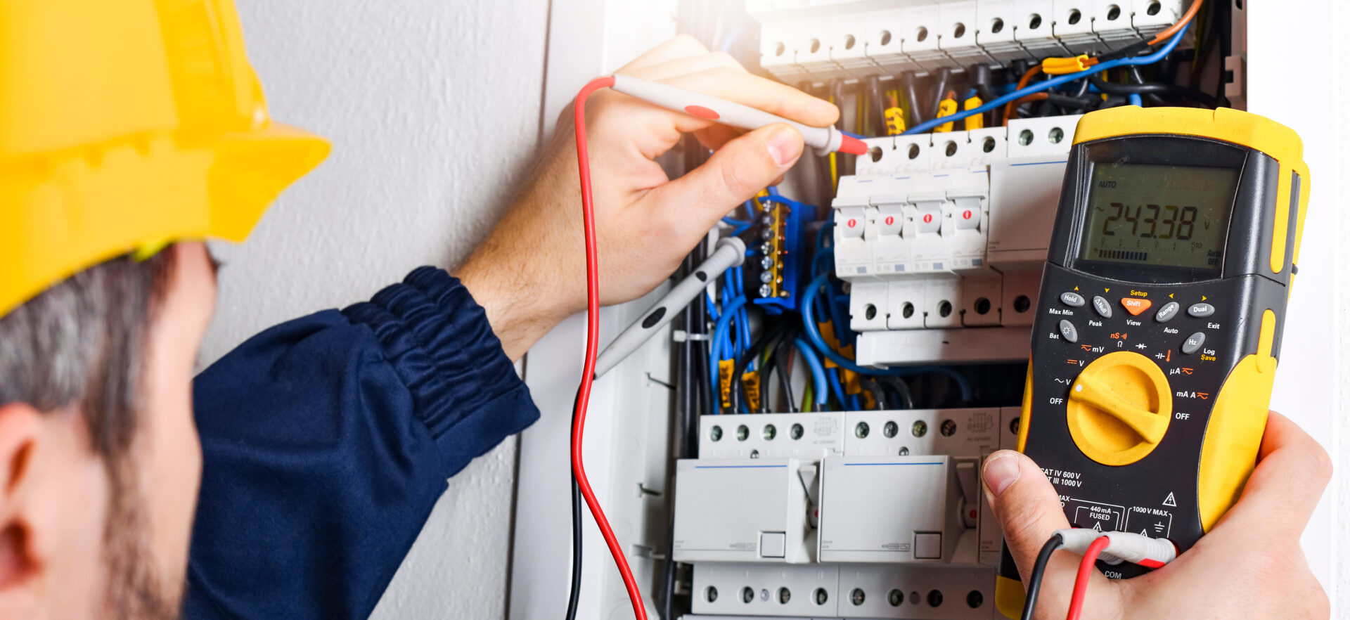 Electrician installing electric cable wires in a fuse switch box