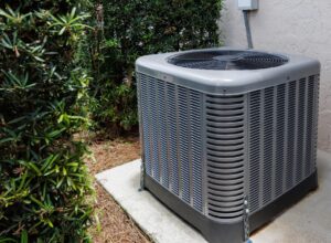 Modern HVAC air conditioner unit on concrete slab outside of house.