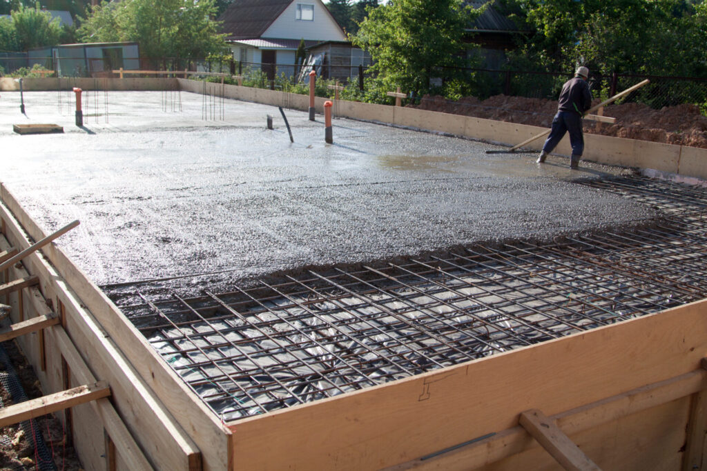 worker leveling fresh concrete slab with a special working tool