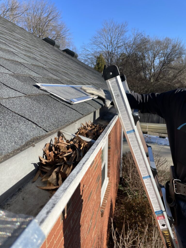 Professional cleaning leaves out of a residential gutter system.