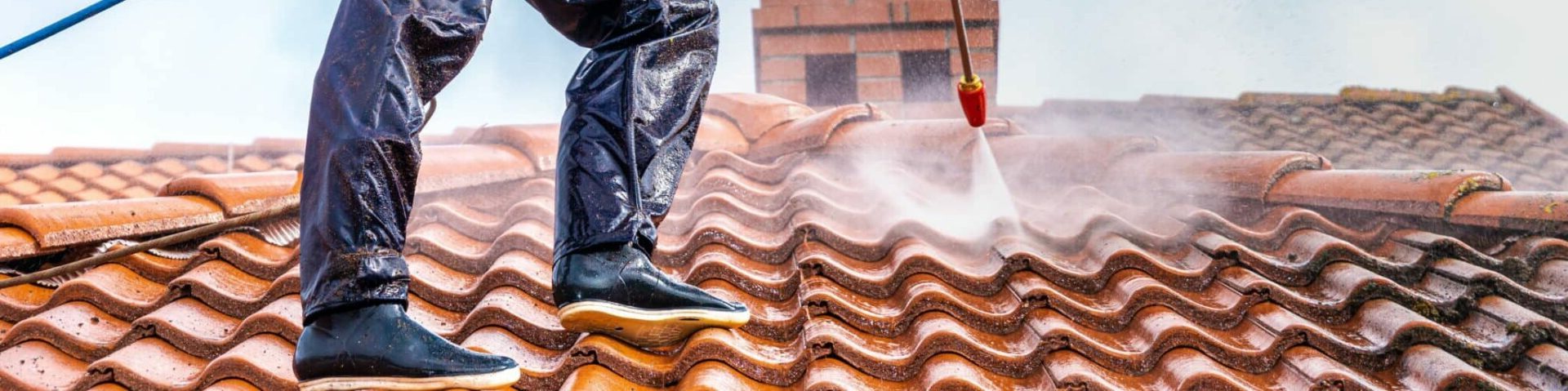 worker washing the roof with pressurized water