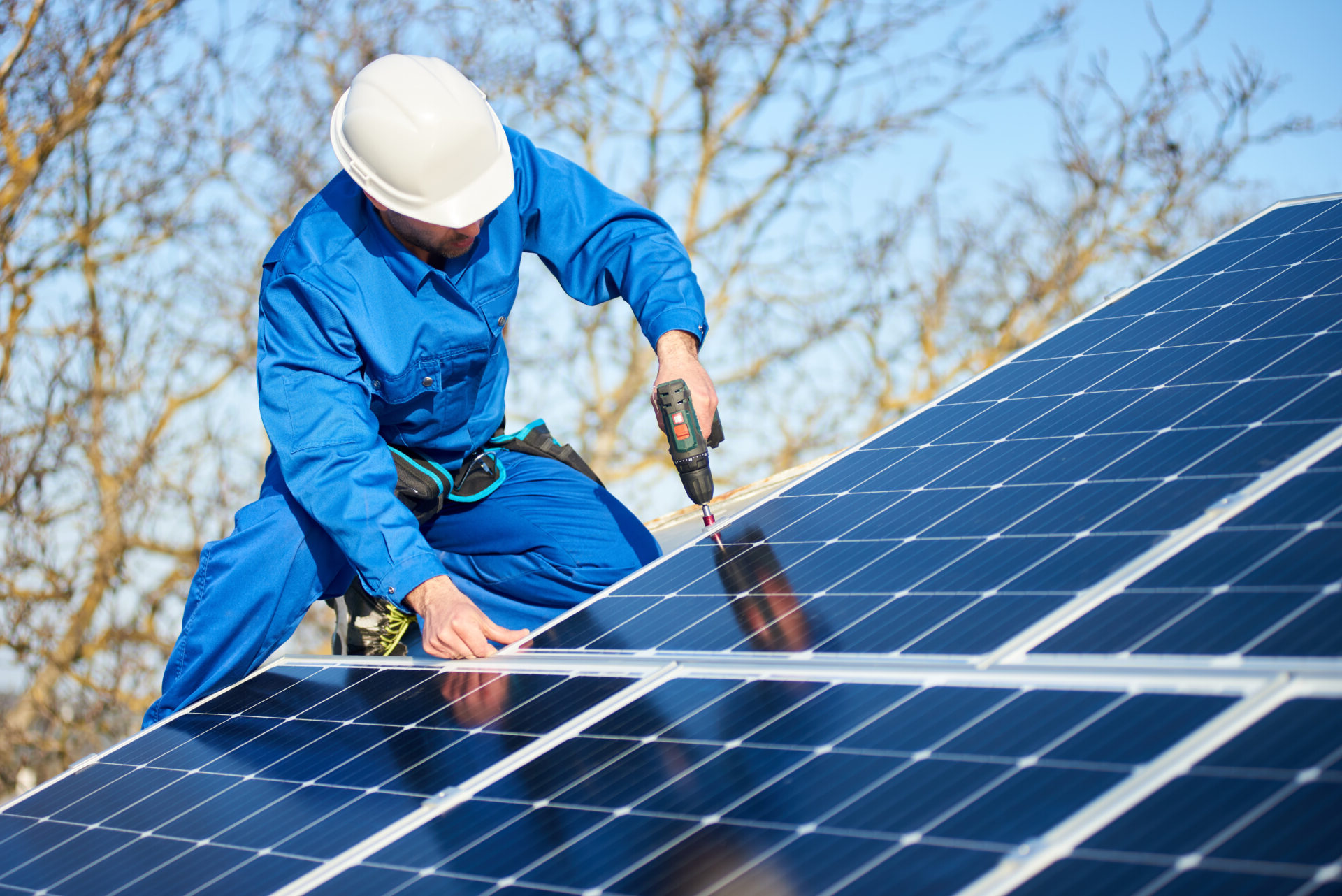 Male engineer in blue suit and protective helmet installing photovoltaic panel