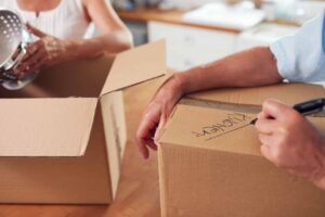 Close Up Of Senior Couple Downsizing In Retirement Boxes Ready For Move Into New Home