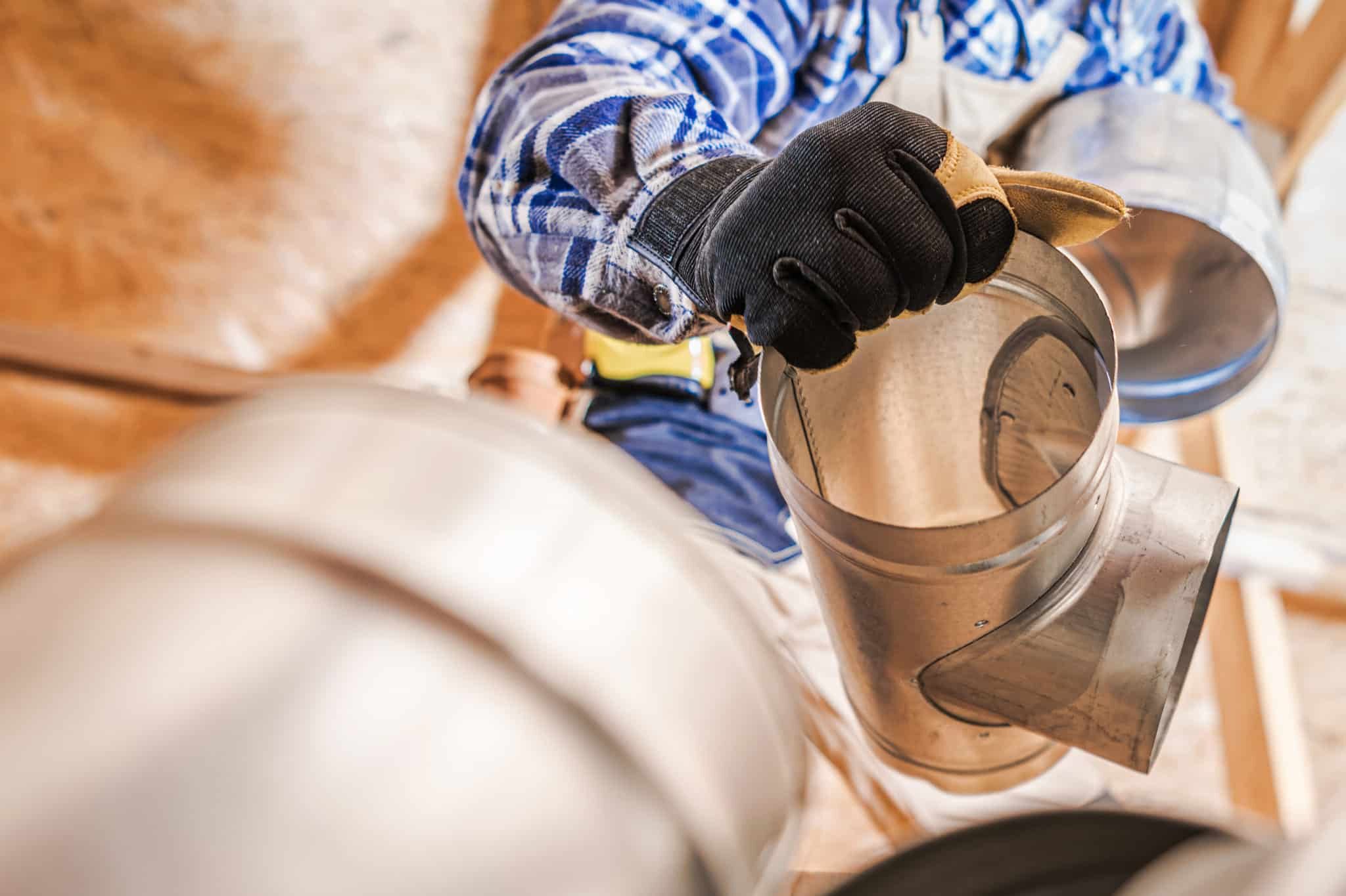 man working on air duct in a house