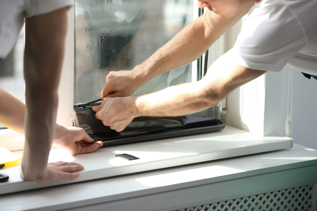 Professional workers tinting a window indoors