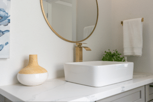 Modern bathroom vanity details of gold faucet with raised basin and decorative gold-trimmed mirror.
