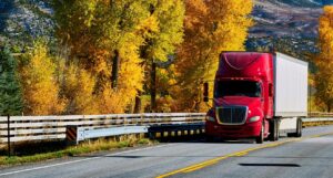 Red moving truck on highway in Colorado at autumn