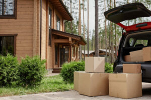modern wooden house in woods with car and cardboard moving boxes in foreground