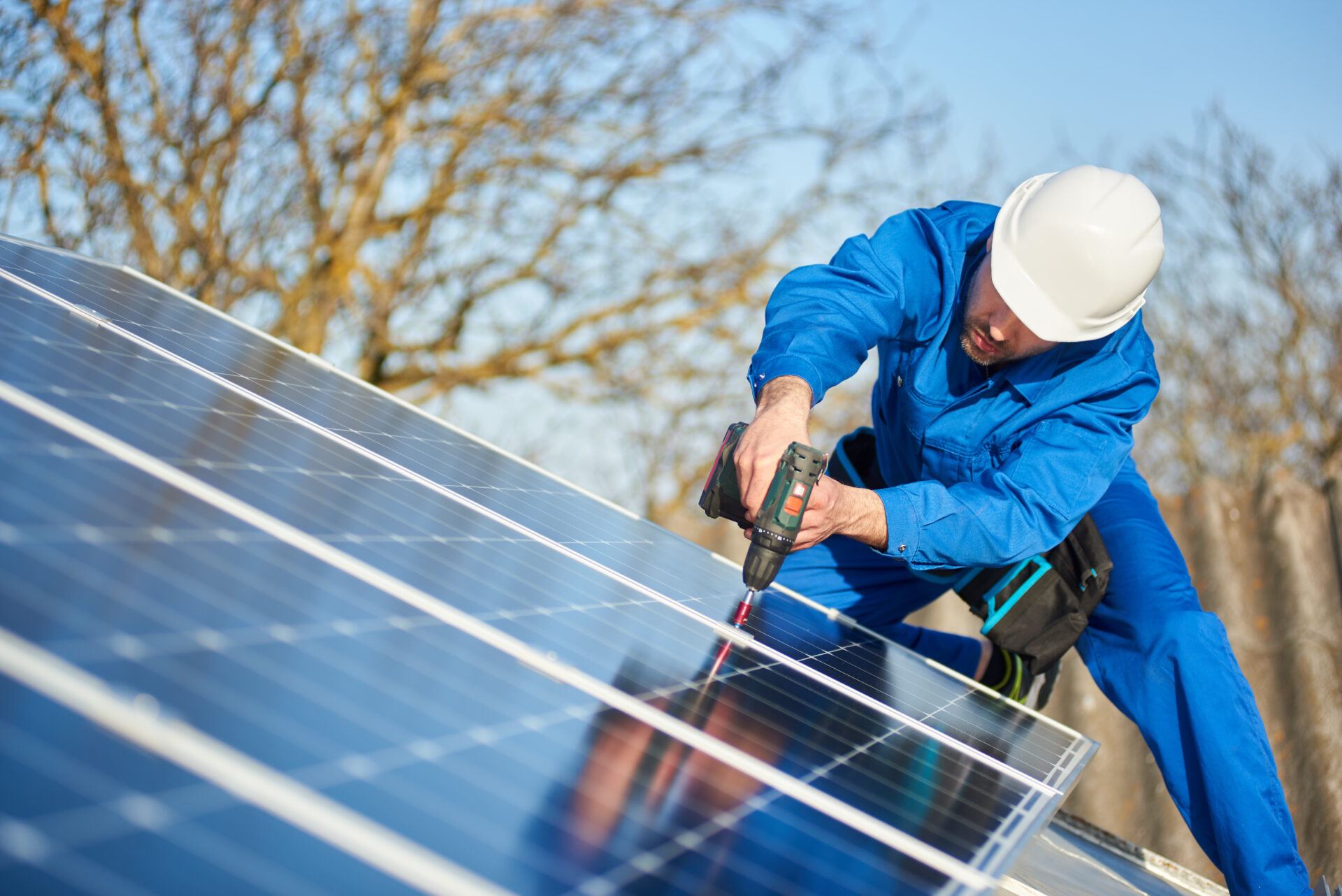 electrician in blue suit and protective helmet installing stand-alone solar panel