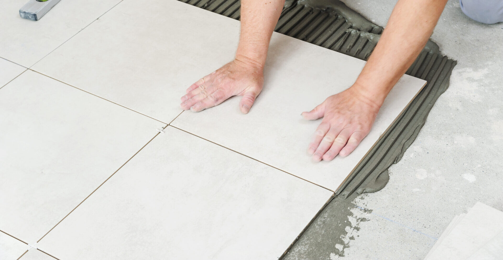 A worker presses a ceramic tile onto the floor