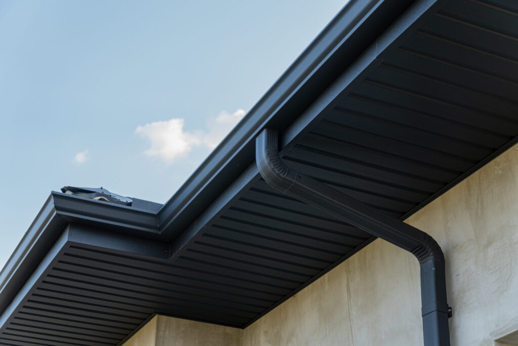 Close-up of a house with black seamless gutters and downspout