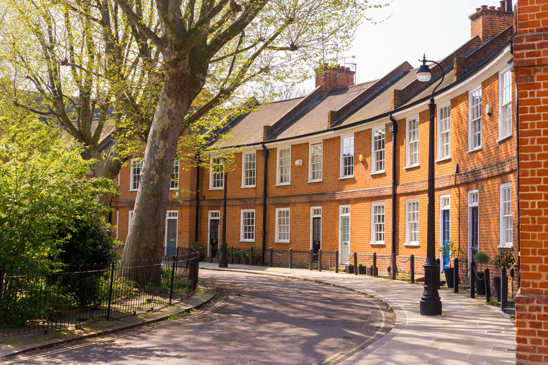 Classic British crescent with restored Victorian red brick houses on a local road with small garden in front