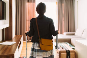 Woman walking into a hotel room with a suitcase in hand. Temporary housing concept.