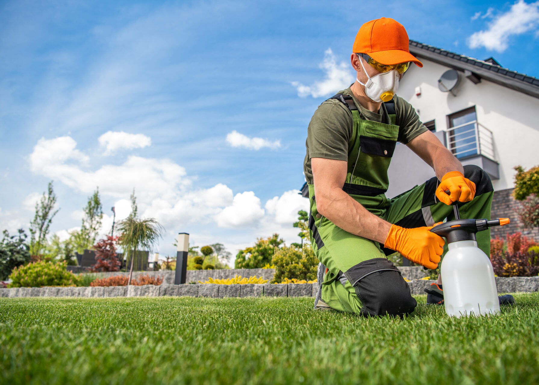 Professional Wearing Full Face Mask and Safety Glasses Getting Ready to Apply Pesticides on the Lawn Grass