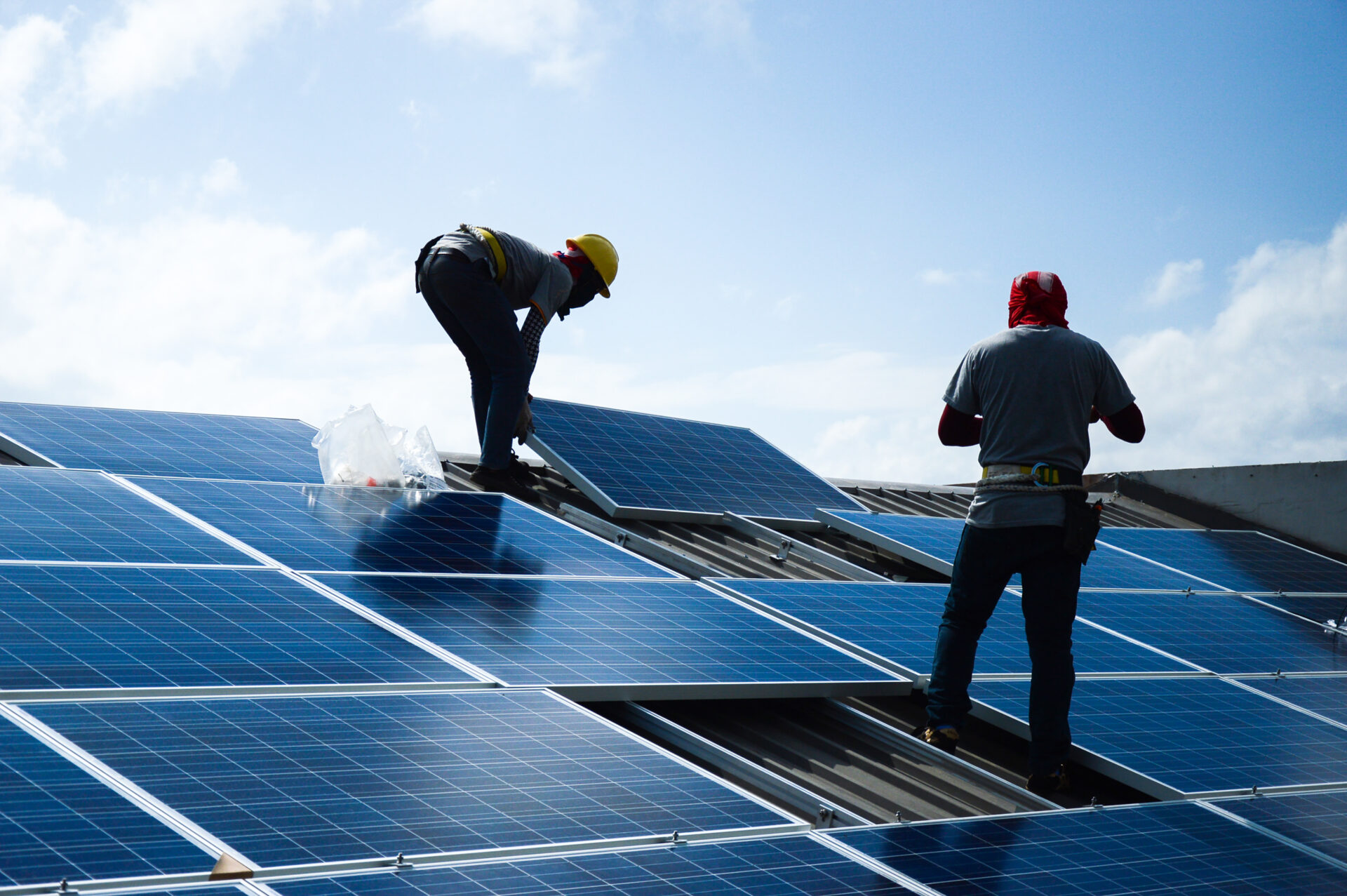 electricians installing solar panels on a roof
