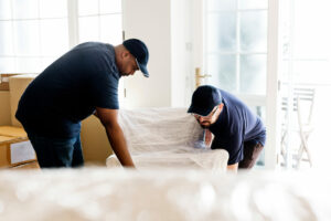 Furniture delivery service concept on moving day. Two people are lifting a couch.