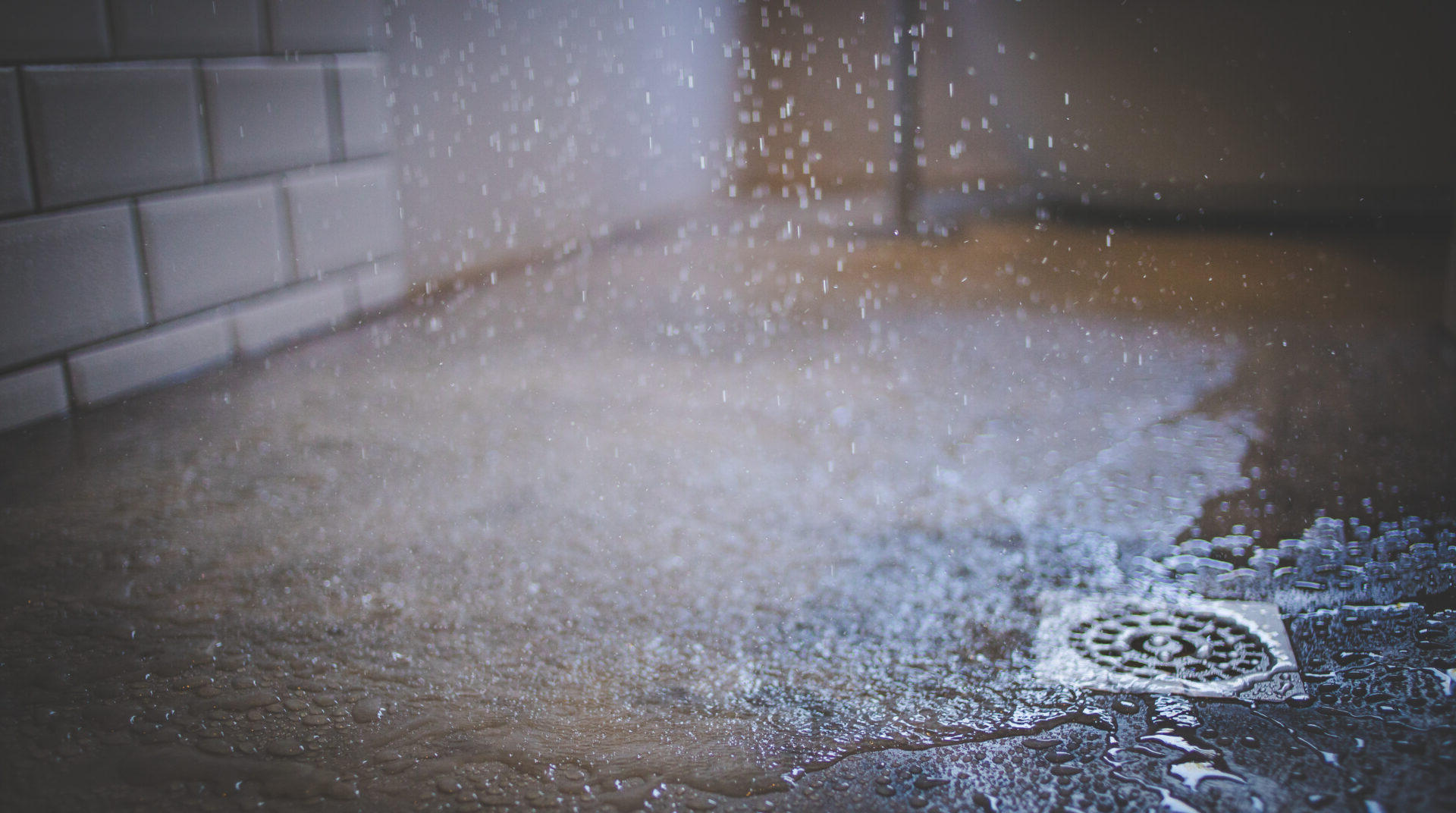 Close up image of water from a shower falling on a shower floor in a luxury bathroom.