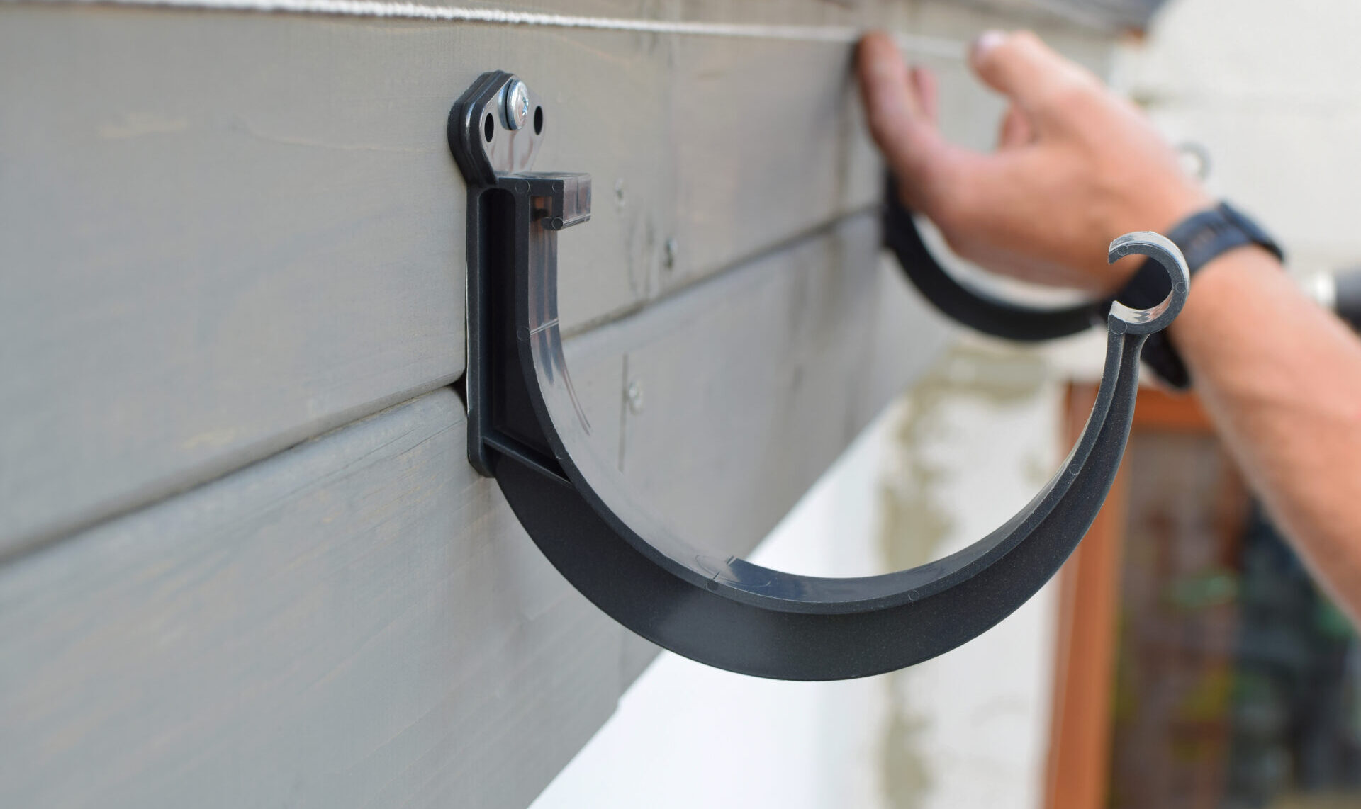 Gutter hangers being installed on a house