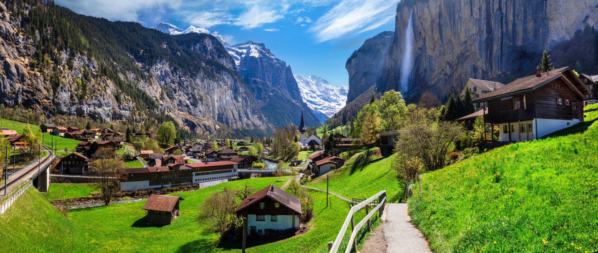 Scenic traditional mountain village lauterbrunnen with waterfall surrounded by snow peaks of Alps.