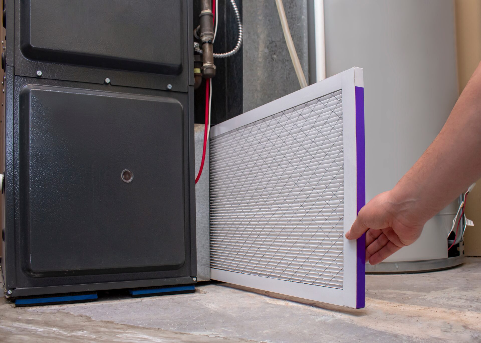 A person changing a clean air filter on a high efficiency furnace