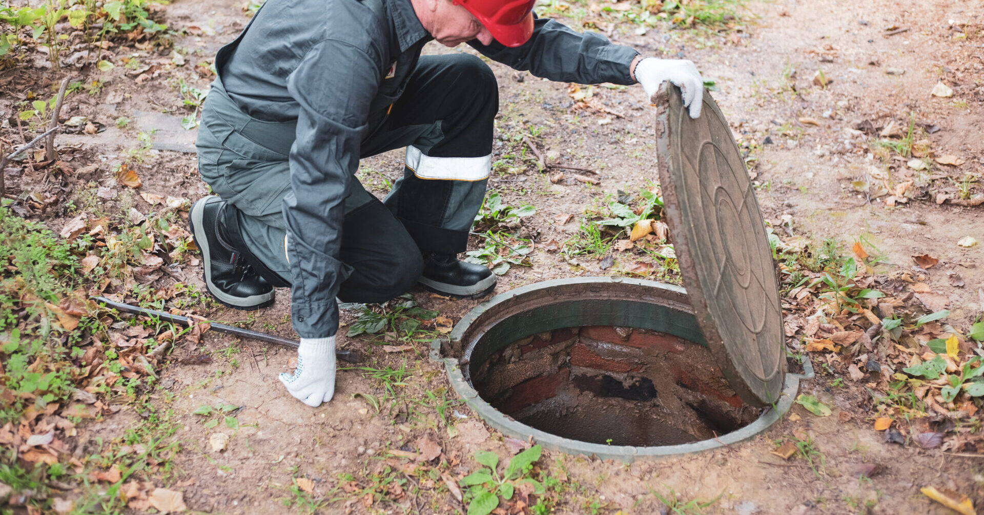 plumber opening a septic tank hatch for inspection