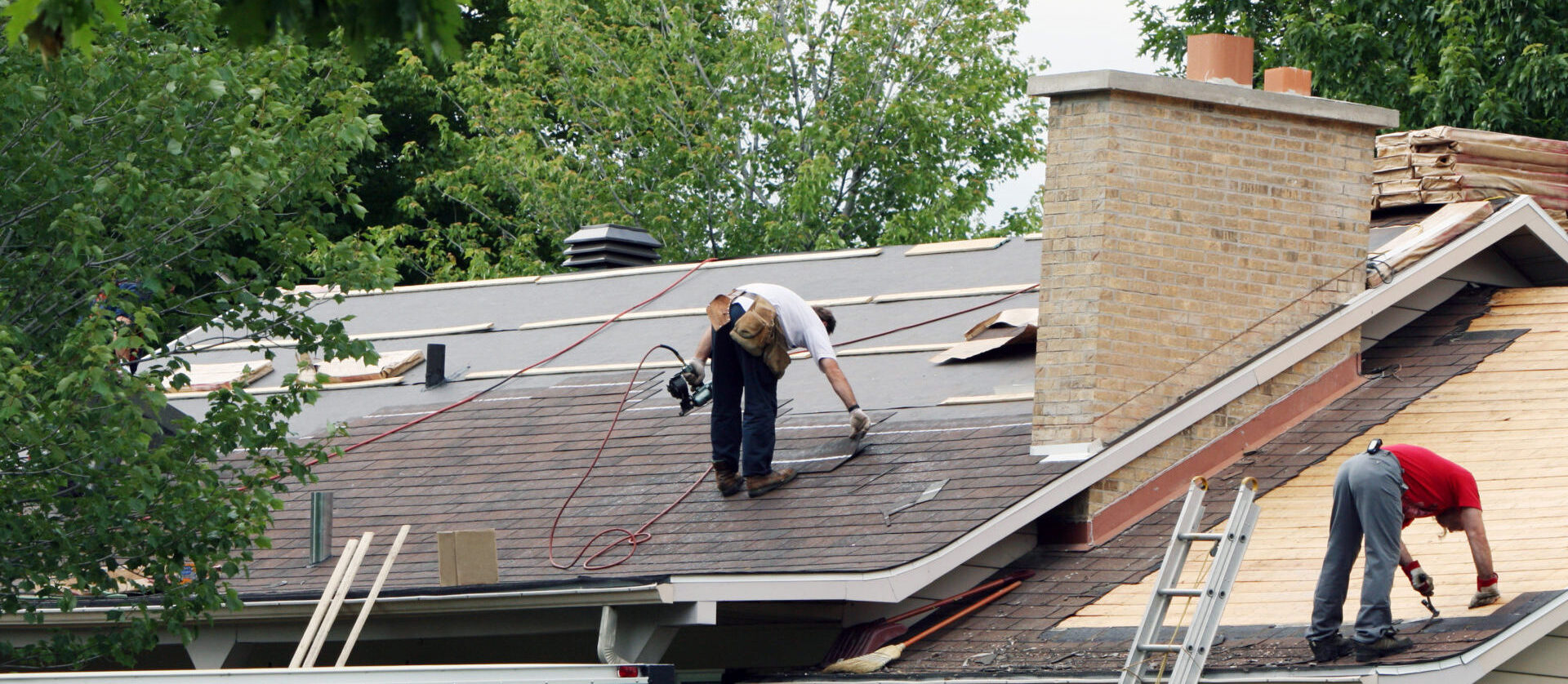 Roof repair workers installing new roof tiles on a roof.