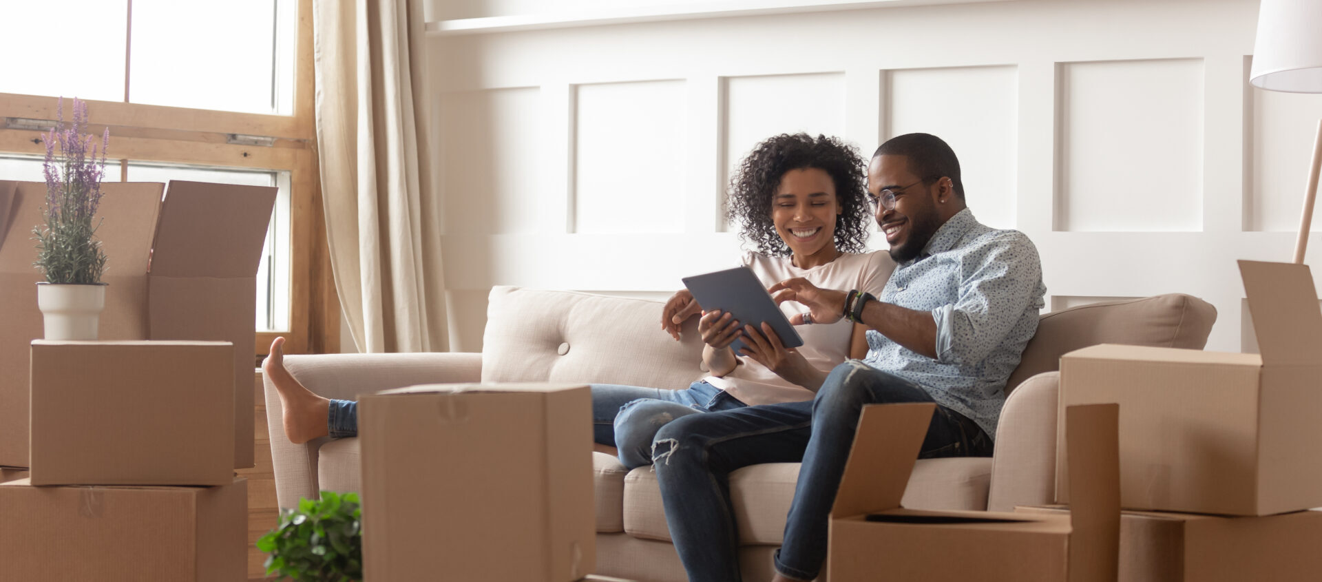 Happy couple sitting around packed boxes planning for a move