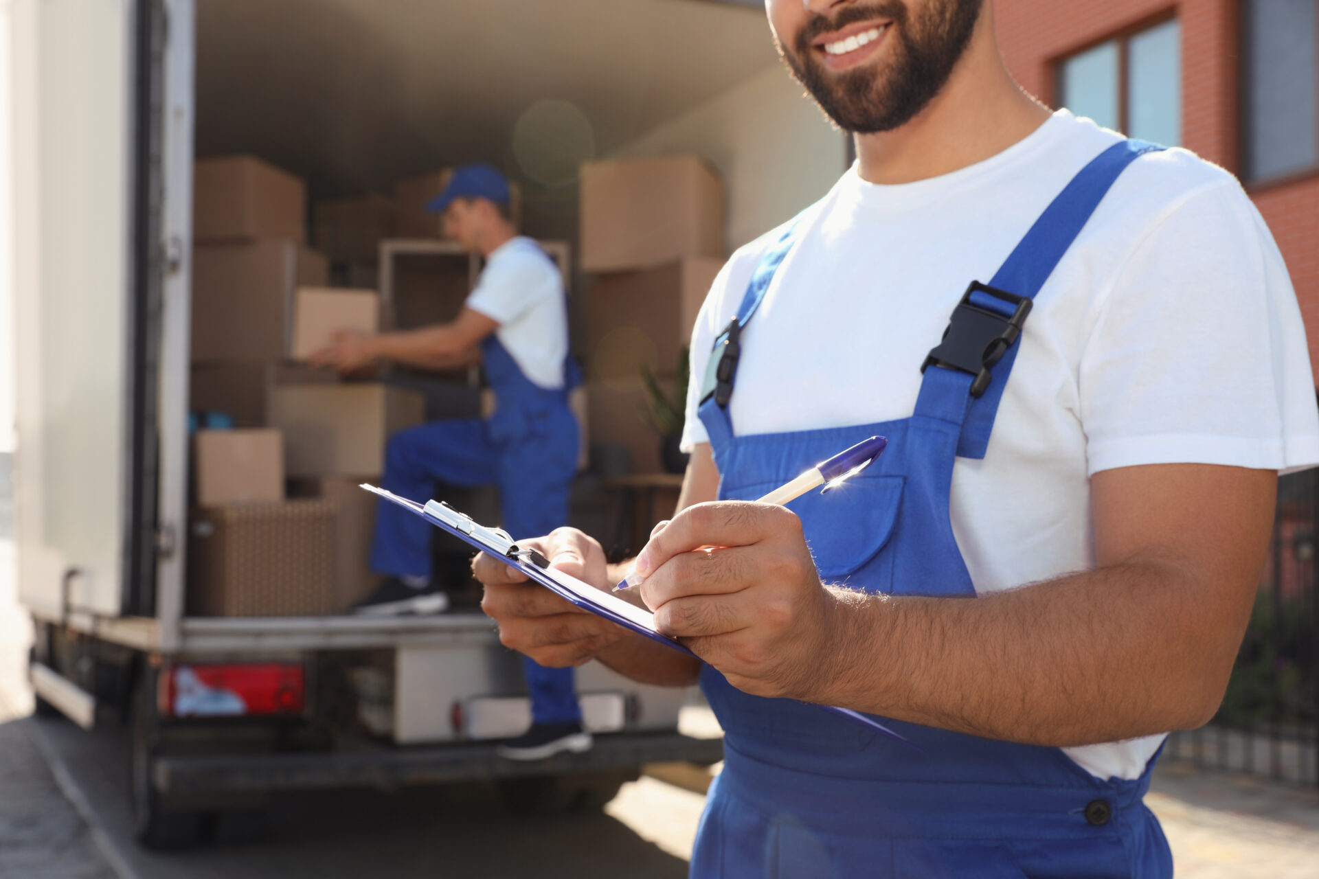 professional mover writing on a notepad in front of a moving truck