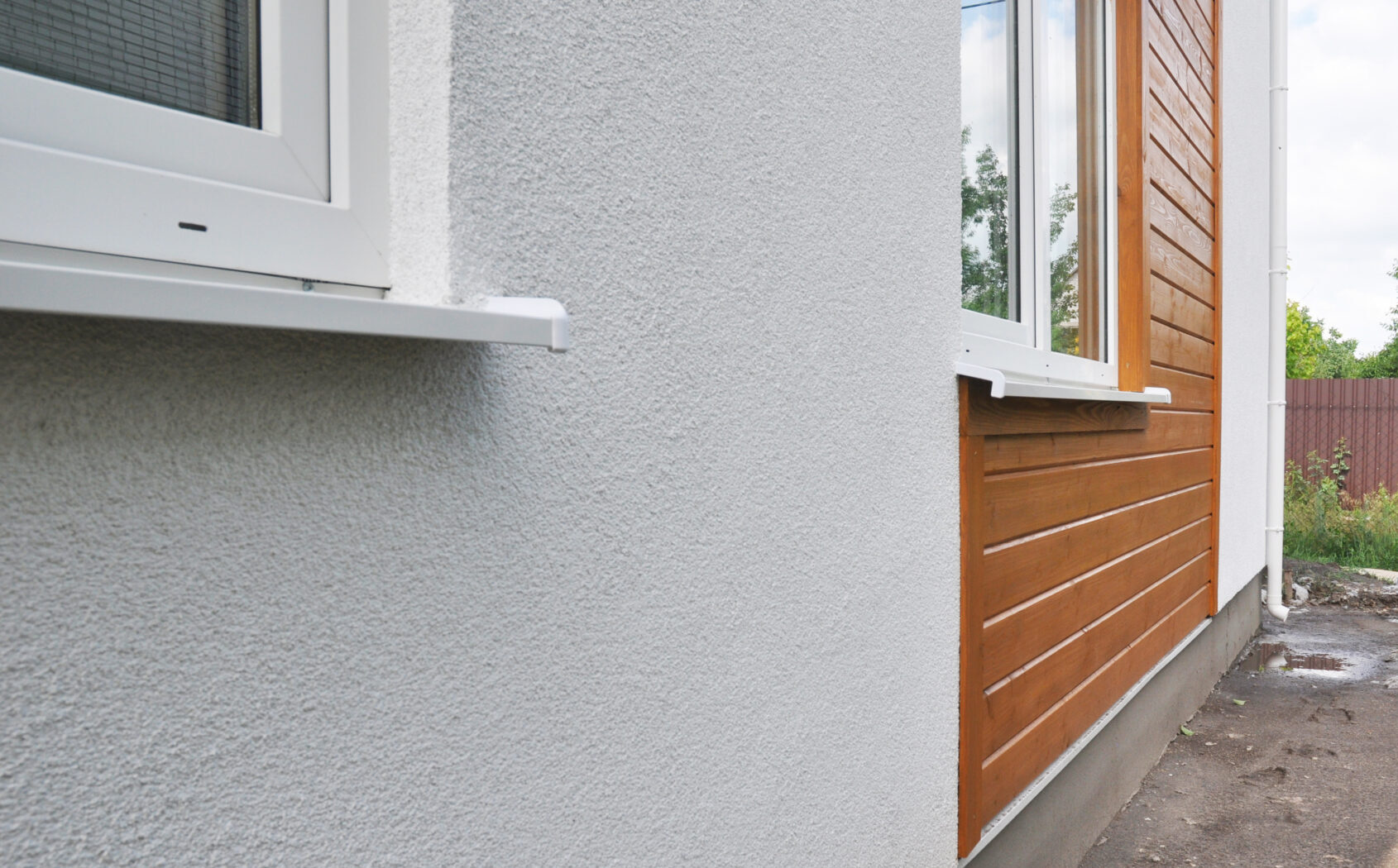 Modern house facade insulation under plastering, stucco and wood wall siding. The combination of stucco and wood siding, wood cladding on the external house wall.