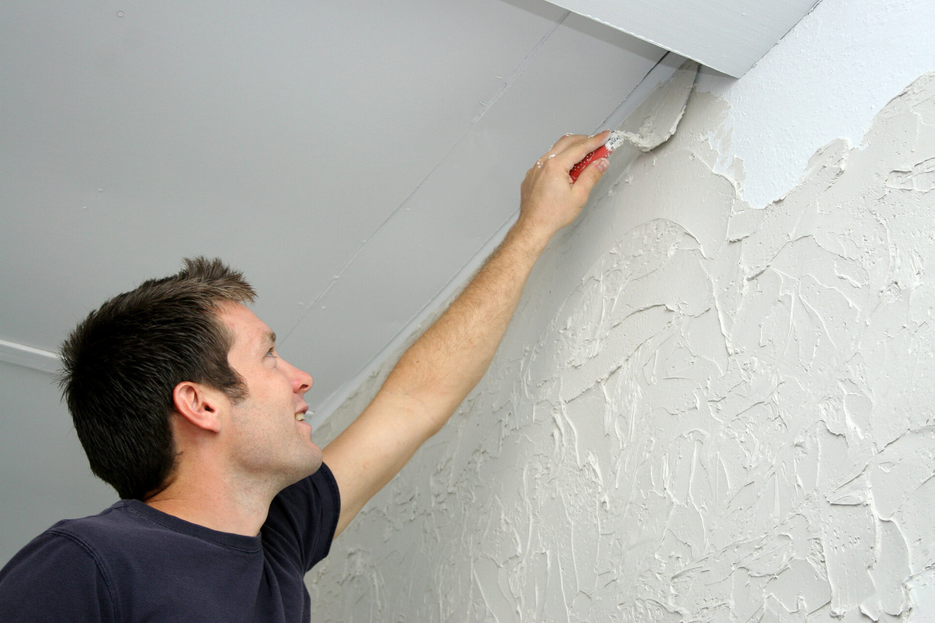 Man texturizing wall with sheetrock mud.