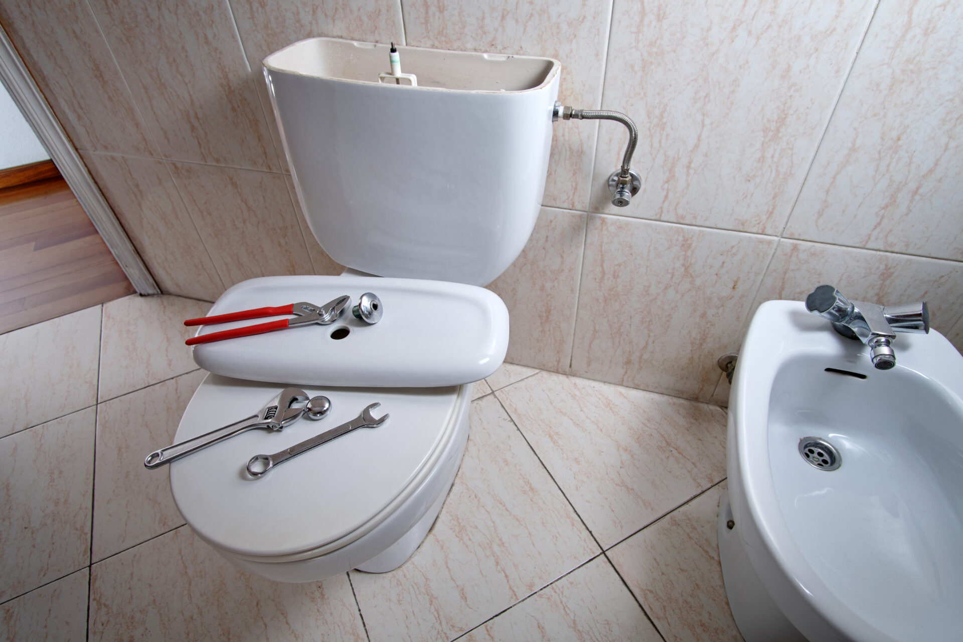 Open and damaged toilet cistern with tools for repair