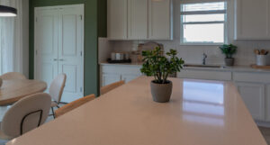 Farmhouse style kitchen with white Corian counter, black hanging pendant lights and kitchen island.