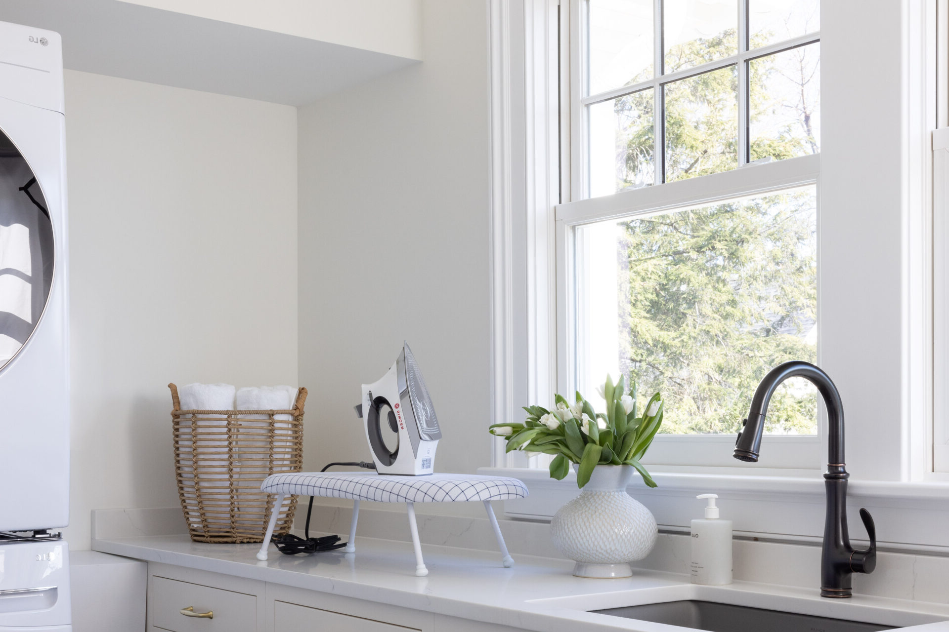 Bright modern laundry room with sink, iron, and mini ironing board