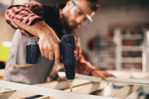 A handyman drilling into a wooden frame.