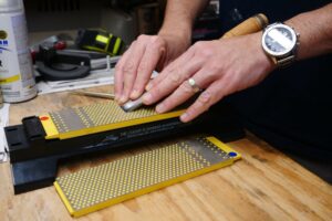 sharpening a blade on a sharpening stone on a workbench