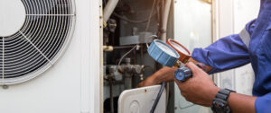 HVAC system service technician using measuring manifold gauge checking refrigerant and filling industrial air conditioner after duct cleaning.