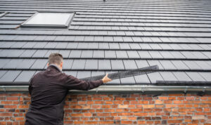 Man puts a gutter mesh to the rain gutter to protect the gutter from leaves.