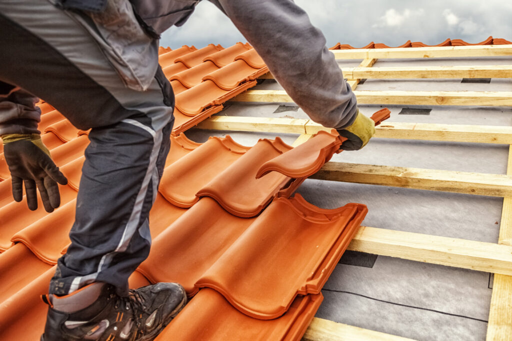 Roofer at work, installing clay roof tiles.