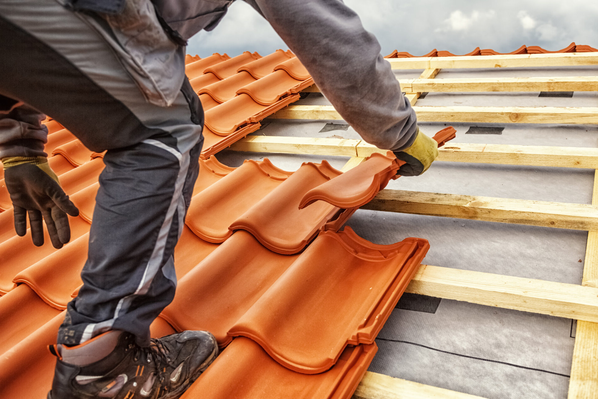 Roofer at work, installing clay roof tiles.