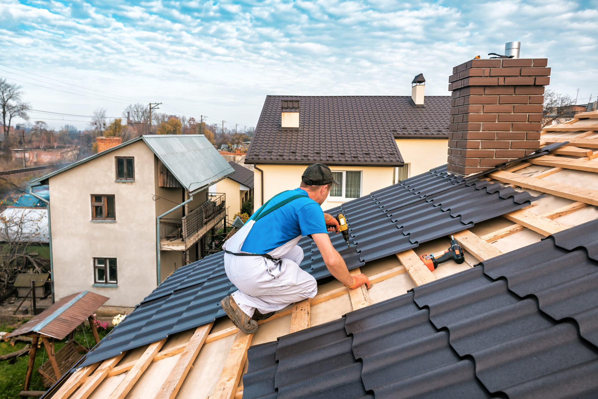 a professional master (roofer) with electric screwdriver covers repairs the roof
