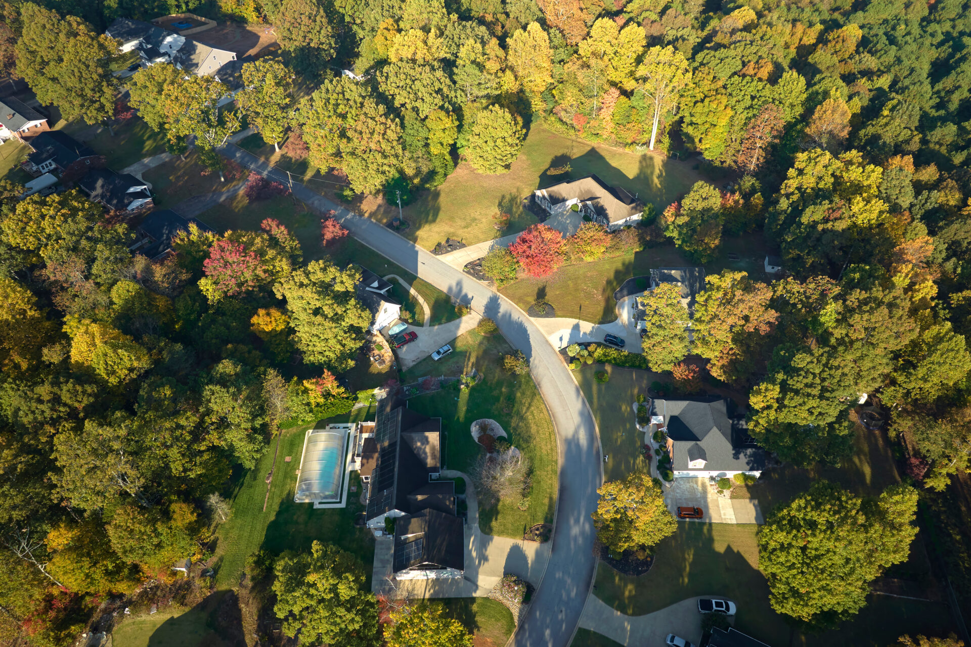 View from above of expensive residential houses between yellow fall trees in suburban area in South Carolina. American dream homes as example of real estate development in US suburbs.