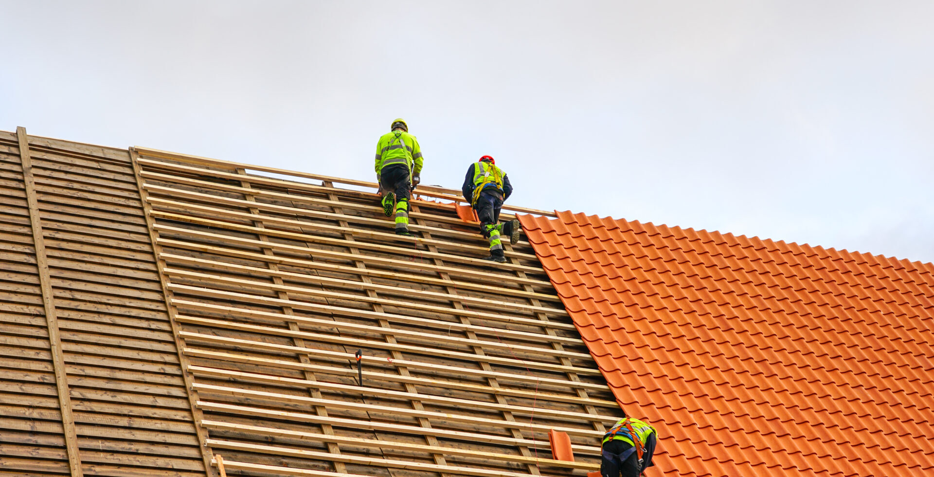 Three workers laying new clay tile roof.