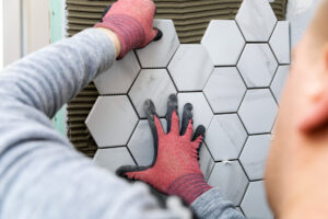 Man laying hexagon tiles on the wall.